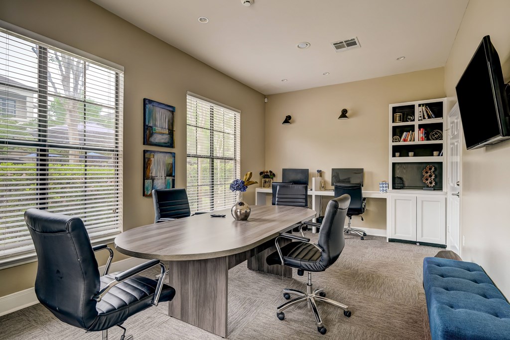 A conference room with a large table surrounded by chairs.